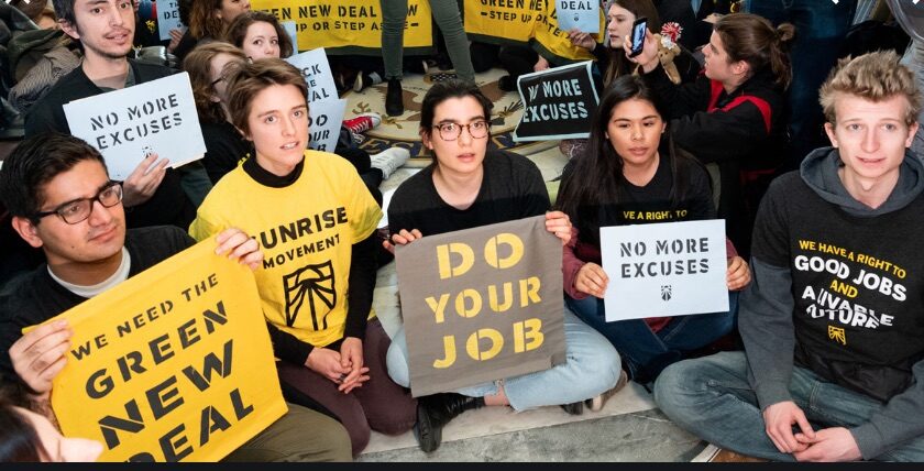 A group of people sitting on the ground holding signs.