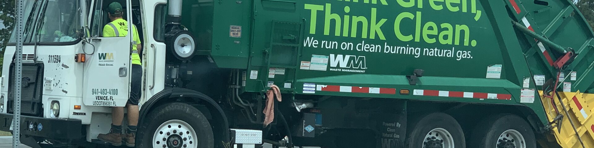 A garbage truck is parked on the side of the road.